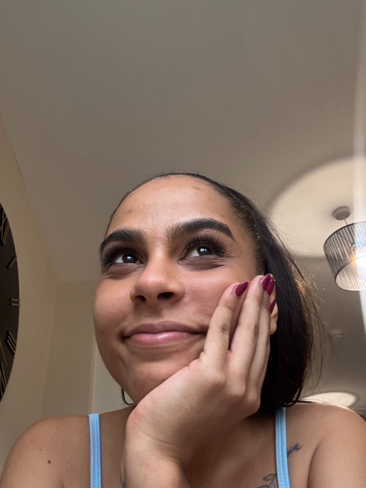 Ana resting her chin on her hand and smiling in a light blue top