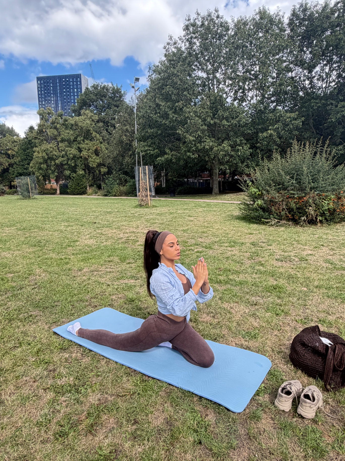 Ana kneeling in a meditative pose on a yoga mat outdoors