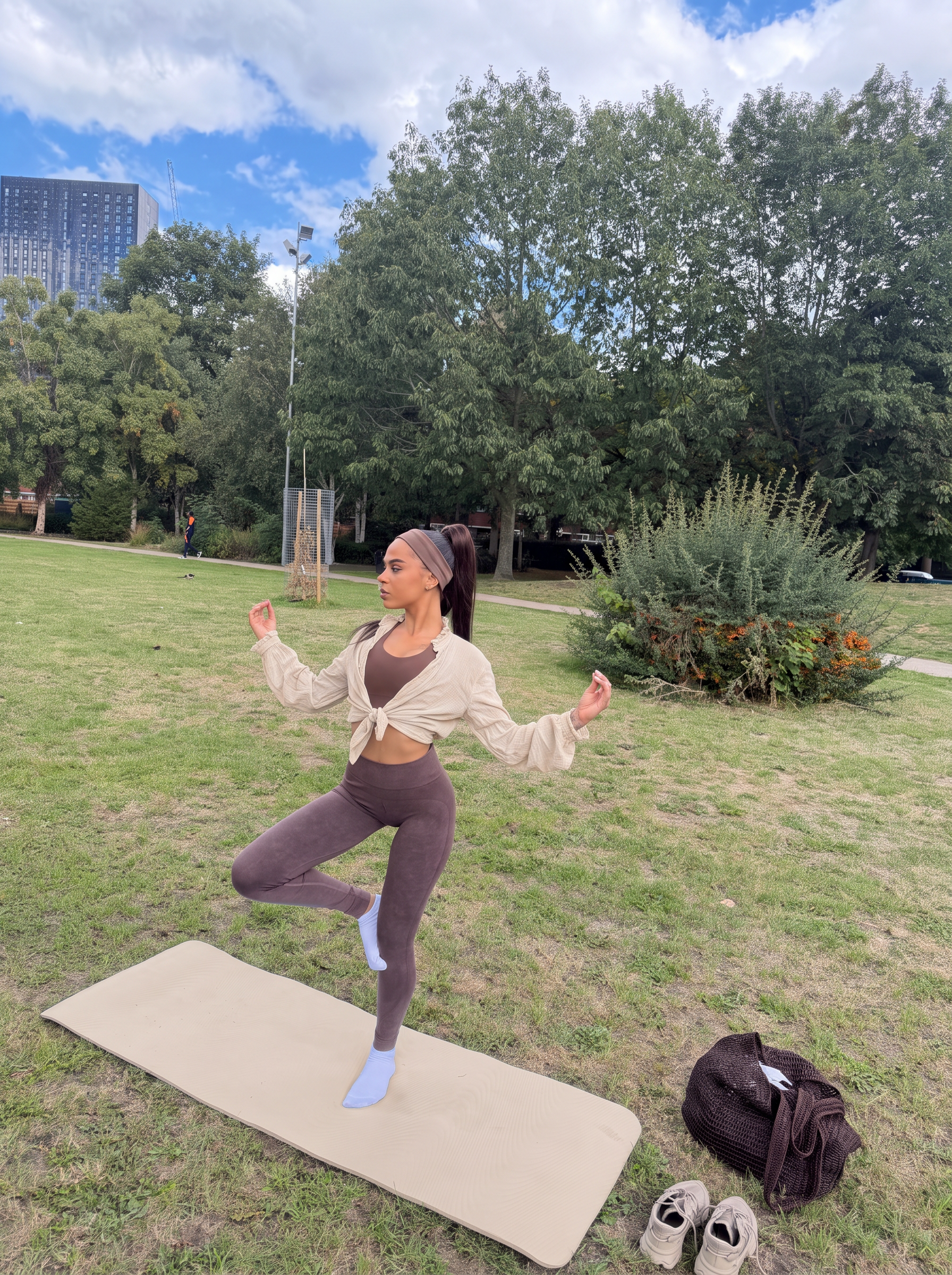 Ana in a beige shirt balancing on a beige yoga mat in a Manchester park